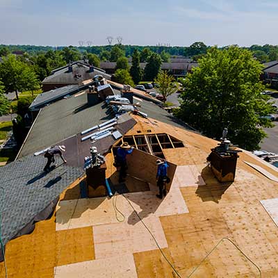 Workers replacing the wooden sheathing and shingles of a residential roof